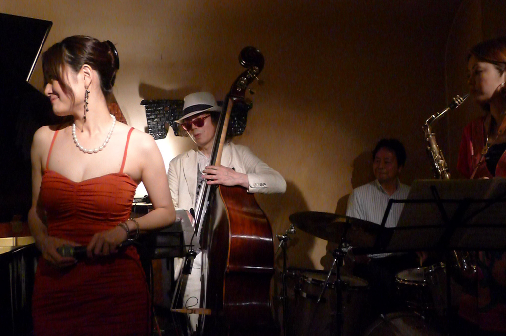 Figure 2: Naoko Akimoto (vocals), Ken Nakayama (bass), Shuichi Uchida (drums), and Naomi Komoto (sax) at Yoyogi Naru (June 2012)